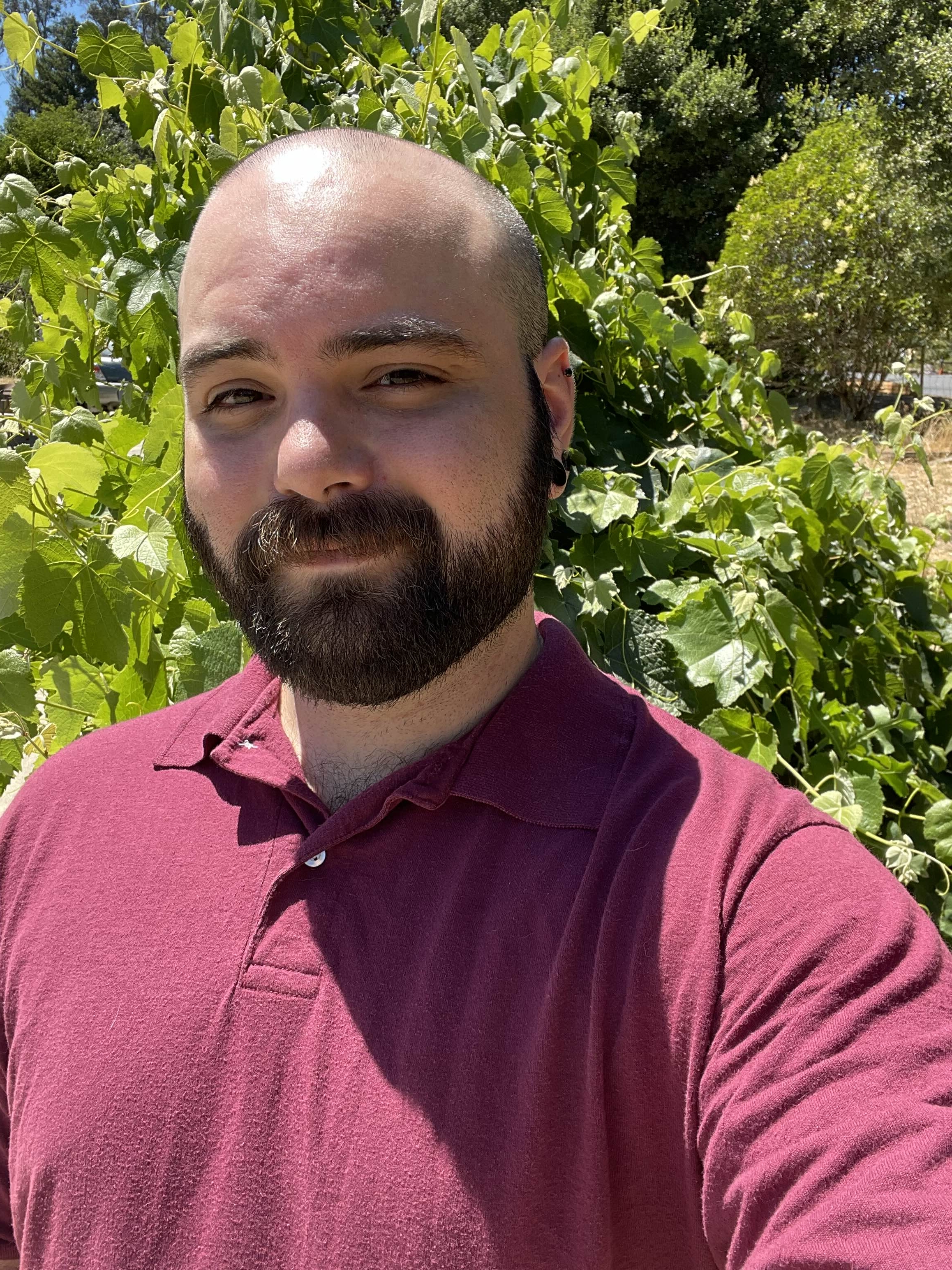 Individual standing in front of a bush looking forward